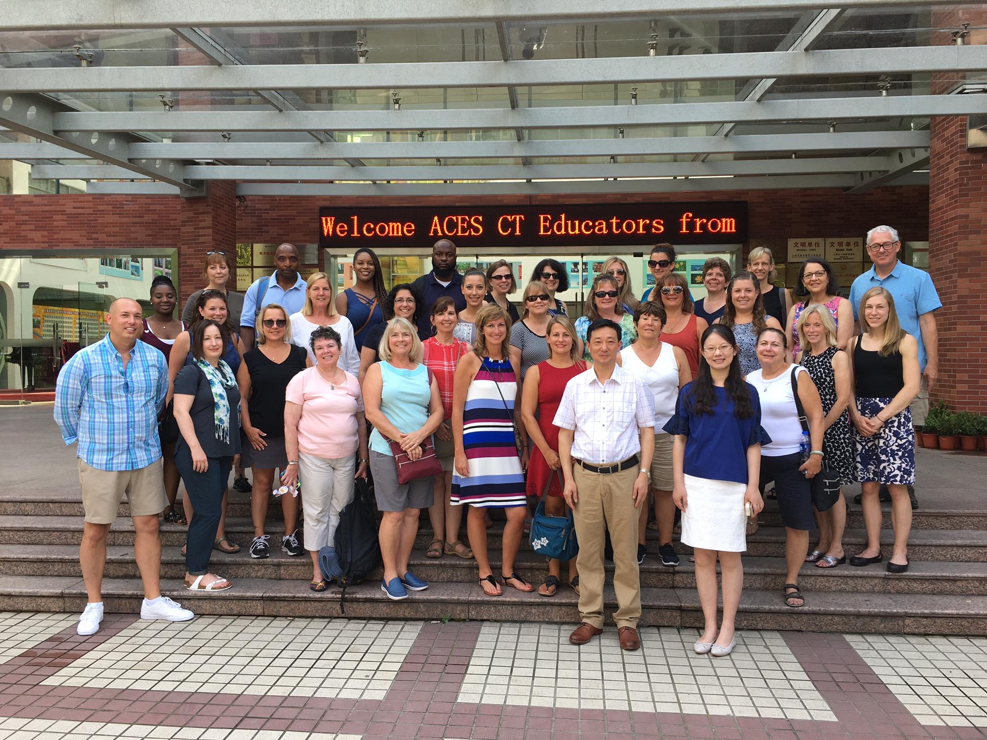 The entire ACES ECA educators field study group pose for a photo in front of a sign welcoming them.